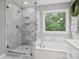 Bright bathroom featuring a glass shower, soaking tub, and window with natural light at 2821 Providence Spring Ln, Charlotte, NC 28270