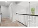 Upstairs hallway with neutral walls and carpet, featuring a window and a black handrail at 2821 Providence Spring Ln, Charlotte, NC 28270