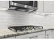 Close-up of a gas cooktop beneath a microwave, complemented by white subway tiles and granite countertops at 2821 Providence Spring Ln, Charlotte, NC 28270