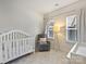 Cozy Bedroom with a white crib, gray rocking chair, and soft lighting from a modern floor lamp at 513 Cubitt Ct, Charlotte, NC 28205