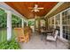 Spacious covered patio featuring tile floors, wood ceiling, ceiling fans, and comfortable seating with wooded views at 6324 Old Fox Hunt Ln, Mint Hill, NC 28227