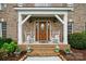 Covered porch featuring rocking chairs, brick steps and wood front door with glass detailing at 6324 Old Fox Hunt Ln, Mint Hill, NC 28227