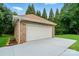 Detached brick garage with a clean white garage door and ample parking space surrounded by trees at 6324 Old Fox Hunt Ln, Mint Hill, NC 28227