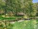 Lakeside view of a beautiful house surrounded by large shade trees, lush green lawn, and wooden dock at 643 Baron Rd # 8, Waxhaw, NC 28173