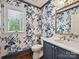 Charming powder room featuring floral wallpaper, marble countertop, and a bronze mirror at 643 Baron Rd # 8, Waxhaw, NC 28173