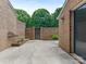 View of backyard featuring a gate, brick wall, greenery, and a concrete foundation at 6817 Dumbarton Dr, Charlotte, NC 28210