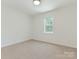 Carpeted bedroom featuring a window allowing natural light, neutral walls, and conveniently placed outlets at 6817 Dumbarton Dr, Charlotte, NC 28210