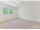 A well-lit bedroom featuring carpet flooring, two windows, neutral walls, and electrical outlets at 6817 Dumbarton Dr, Charlotte, NC 28210