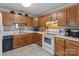 Functional kitchen with wooden cabinets, white appliances, and neutral countertops at 716 Mooresville Rd, Salisbury, NC 28144