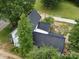 Aerial view of a farmhouse with a black metal roof surrounded by trees at 828 N Main St, Mount Pleasant, NC 28124