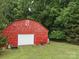 Rustic red barn with a white garage door in a grassy, wooded lot at 828 N Main St, Mount Pleasant, NC 28124