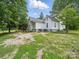 Two-story farmhouse with a black metal roof, surrounded by lush greenery at 828 N Main St, Mount Pleasant, NC 28124