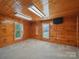 Cozy living room featuring knotty pine walls, carpet, and two windows at 828 N Main St, Mount Pleasant, NC 28124