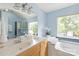 Serene bathroom with blue walls, a garden tub, and a glass block window for natural light at 9004 Lauriston Pl, Mint Hill, NC 28227
