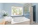 Inviting bathroom featuring a relaxing soaking tub, blue tile accents, and natural light at 9004 Lauriston Pl, Mint Hill, NC 28227