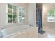 Bright white bathroom with large soaking tub and a shower with floral print at 901 Brighton Dr, Kannapolis, NC 28081
