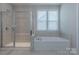 Bright bathroom with glass shower, soaking tub, and large window at 1048 Harbor Bay Dr, Indian Land, SC 29707