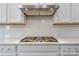 Modern cooktop with stainless steel hood and white subway tile backsplash at 1048 Harbor Bay Dr, Indian Land, SC 29707
