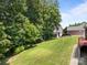 Lush green backyard with a gentle slope leading up to a red brick house and detached garage amid mature trees at 10501 Mount Olive Dr # 7, Mount Pleasant, NC 28124