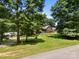 Large yard with mature trees surrounding a brick home with lush green lawn at 10501 Mount Olive Dr # 7, Mount Pleasant, NC 28124