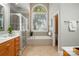 Bright bathroom with a soaking tub, separate shower, and a large arched window with natural light at 10607 Newberry Park Ln, Charlotte, NC 28277