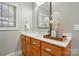 Well-lit bathroom featuring a vanity with wooden cabinets, white countertop and neutral wall paint at 10607 Newberry Park Ln, Charlotte, NC 28277