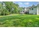 Expansive backyard featuring lush green lawn, mature trees, and a charming white home with a deck at 10874 Rise Ln, Fort Mill, SC 29707