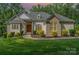 Charming home exterior with a manicured lawn and beautiful landscaping with a wooden front door at 10874 Rise Ln, Fort Mill, SC 29707