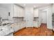 Well-lit kitchen with white cabinetry, granite countertops, and stainless steel appliances, enhanced by warm hardwood flooring at 10874 Rise Ln, Fort Mill, SC 29707