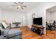 Bright living room boasts hardwood floors, a gray sectional, and a TV with desk setup visible through the doorway at 10874 Rise Ln, Fort Mill, SC 29707