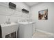 Well-lit laundry room with white washer, dryer, utility sink, and ample storage shelving at 1229 Margo Mannor Dr, Fort Mill, SC 29708
