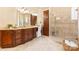 Elegant bathroom featuring tiled floors, dark cabinetry, a glass-enclosed shower, and vanity at 1405 Saratoga Woods Dr, Waxhaw, NC 28173