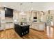 Modern kitchen with black kitchen island, white cabinets, hardwood floors, and stainless steel appliances at 1405 Saratoga Woods Dr, Waxhaw, NC 28173