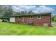 Exterior view of a brick home with a lawn, central air unit, and green hose at 1691 Hill River Rd, Hiddenite, NC 28636