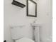 A bright bathroom featuring white walls, a pedestal sink, a black framed mirror, and a standard toilet at 2315 Circle Dr, Great Falls, SC 29055