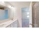 Bathroom with dual sinks, white cabinets, and a doorway to the bedroom at 4009 Lawnview Dr, Charlotte, NC 28269