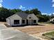 Charming white farmhouse with black trim and a concrete driveway, surrounded by lush green trees at 420 Sloop St, China Grove, NC 28023