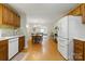 Open kitchen and dining area with wooden cabinets and modern white appliances and wood laminate flooring at 4230 Train Chaser Pl, Indian Land, SC 29707