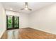 Bright bedroom featuring hardwood floors, ceiling fan, and balcony doors with green trees outside at 428 E 33Rd St, Charlotte, NC 28205