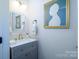 Elegant powder room with gray vanity, gold fixtures, and decorative mirror and artwork at 4323 Bright Rd, Charlotte, NC 28214