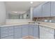 Well-lit kitchen with light blue cabinets, a mosaic backsplash, and a view to the living area at 4557 Panther Pl, Charlotte, NC 28269
