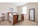 Cozy bedroom with a wooden sleigh bed, neutral carpet, and a large window for natural light at 5130 Watersail Way, Clover, SC 29710