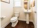 Elegant powder room boasts dark wood floors, pedestal sink, mirror, and toilet with charming fixtures at 5130 Watersail Way, Clover, SC 29710