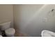 Cozy half bathroom featuring a toilet, wall fixtures, and a small pedestal sink at 5476 Ives Nw St, Concord, NC 28027