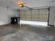 Interior view of a spacious garage with open door and two trash receptacles at 5476 Ives Nw St, Concord, NC 28027