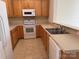 Bright kitchen features wooden cabinets, white appliances, tile flooring, and a breakfast bar at 5476 Ives Nw St, Concord, NC 28027