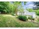View of the backyard featuring mature landscaping, a lush lawn, and a partial view of the home's exterior at 6033 Edinmeadow Ln, Charlotte, NC 28269