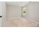Cozy bedroom showcasing neutral walls, soft carpeting, and a sunlit window at 6033 Edinmeadow Ln, Charlotte, NC 28269