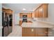 Well-lit kitchen features wood cabinets, black appliances, and neutral countertops with a peninsula and tile floors at 6033 Edinmeadow Ln, Charlotte, NC 28269