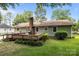 A backyard has a wood deck, a small brick chimney, a grill, and a green lawn at 6231 Coach Hill Ln, Charlotte, NC 28212